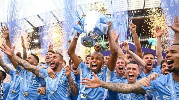 Manchester City players lifting a trophy